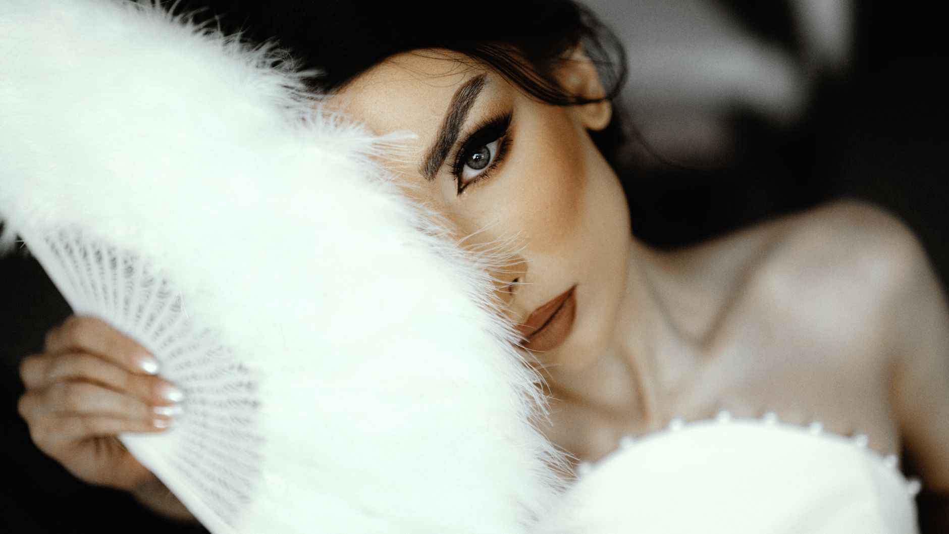Close-up of a bride's face partially hidden by a feather fan, exuding elegance and mystery. — How Bscscan Empowers Traders wi