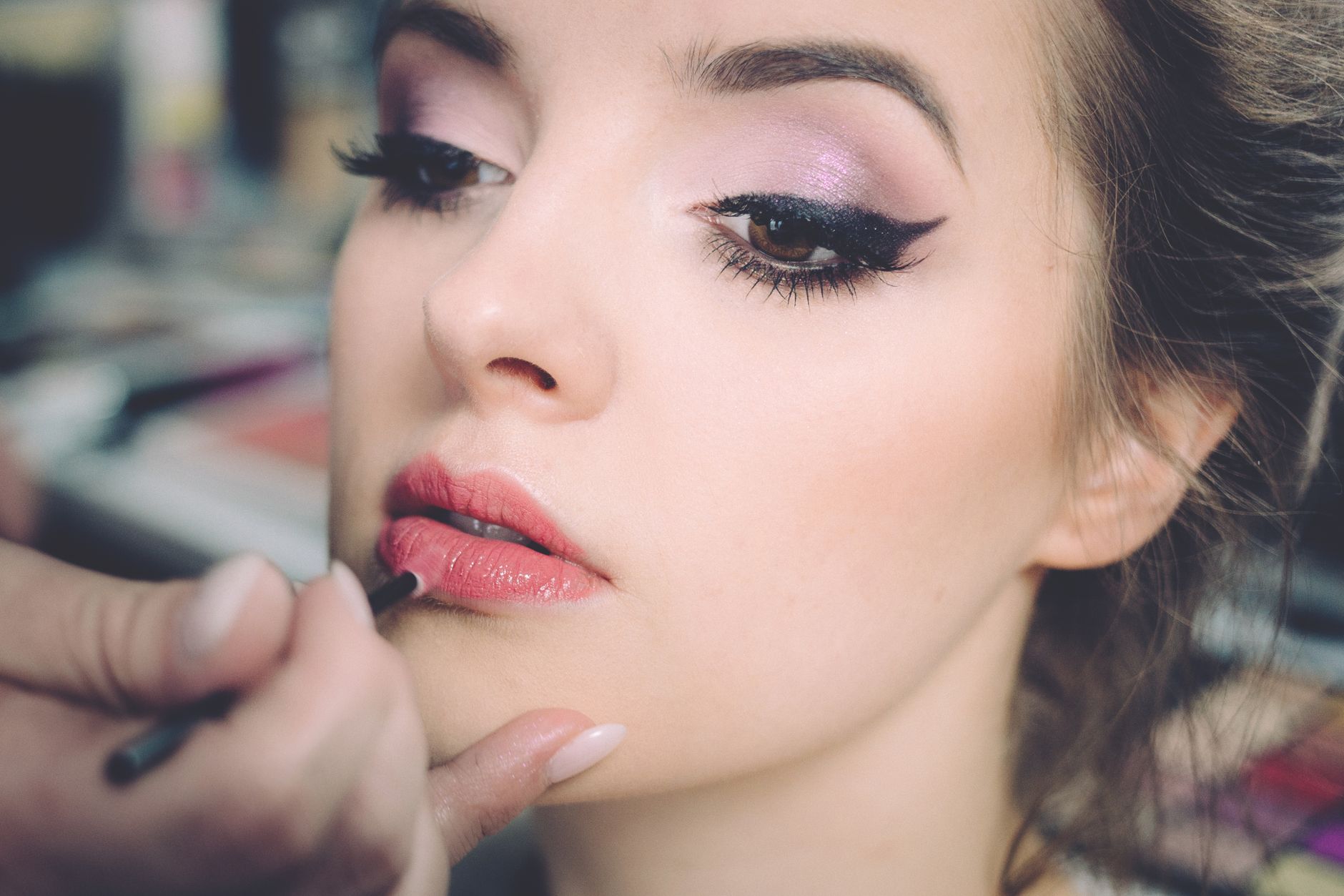 A close-up portrait of a woman getting professional makeup applied indoors, highlighting elegance and beauty. — Maximize Effi